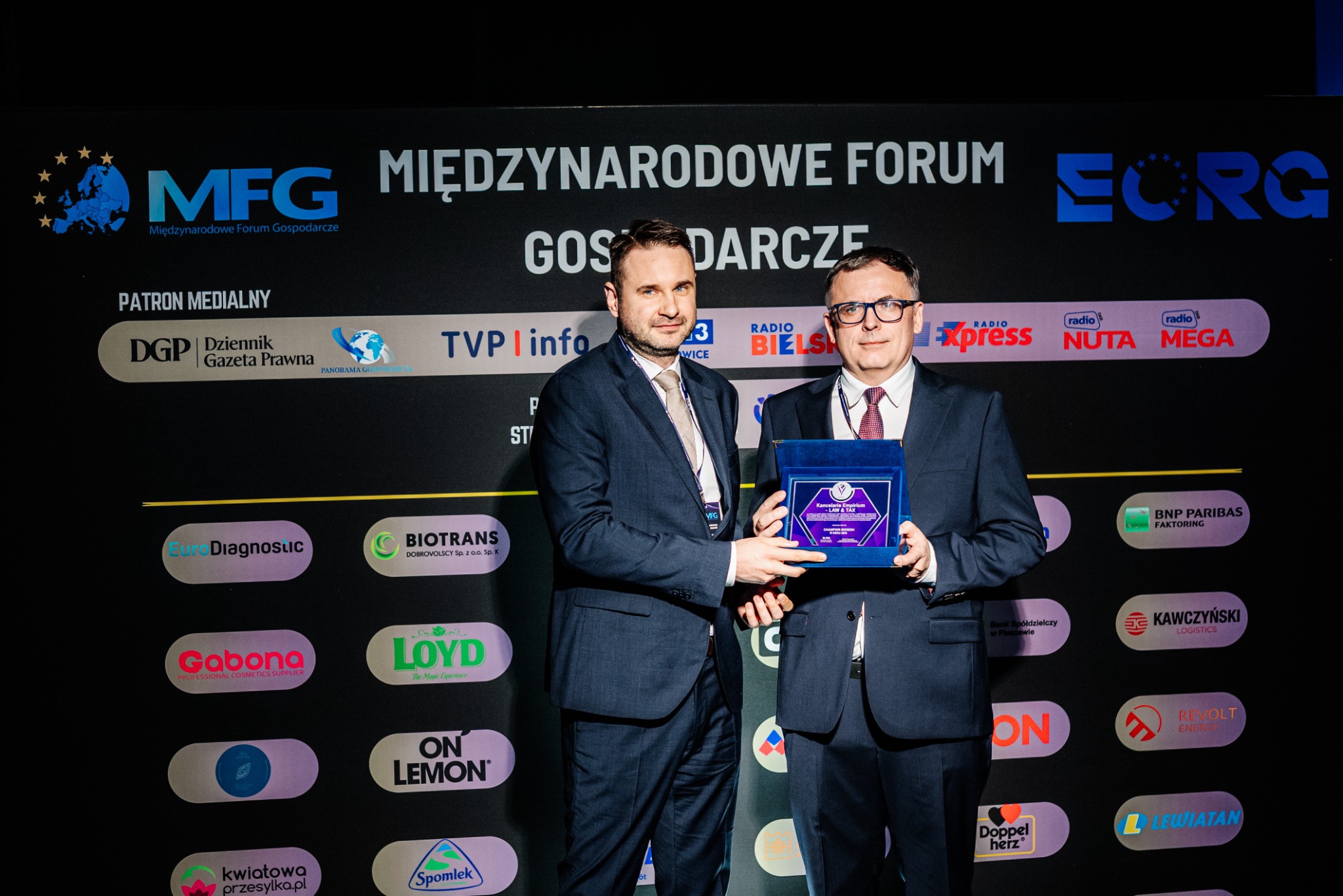 Jakub Jaroń i Adam Klęczar z nagrodą Champion Biznesu 2026 na tle ścianki Międzynarodowego Forum Gospodarczego.